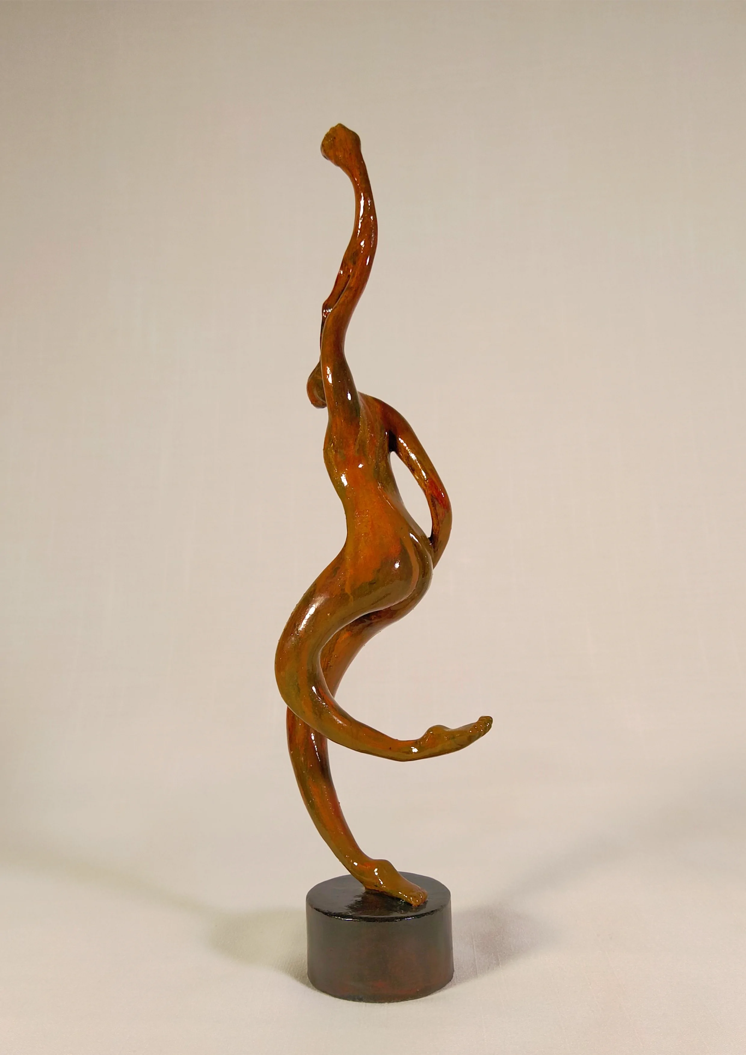 Figura sobre una base redonda con un apoyo, un brazo en alto. Tonos rojos y marrones. 35x7x10 centímetros, 372 gramos