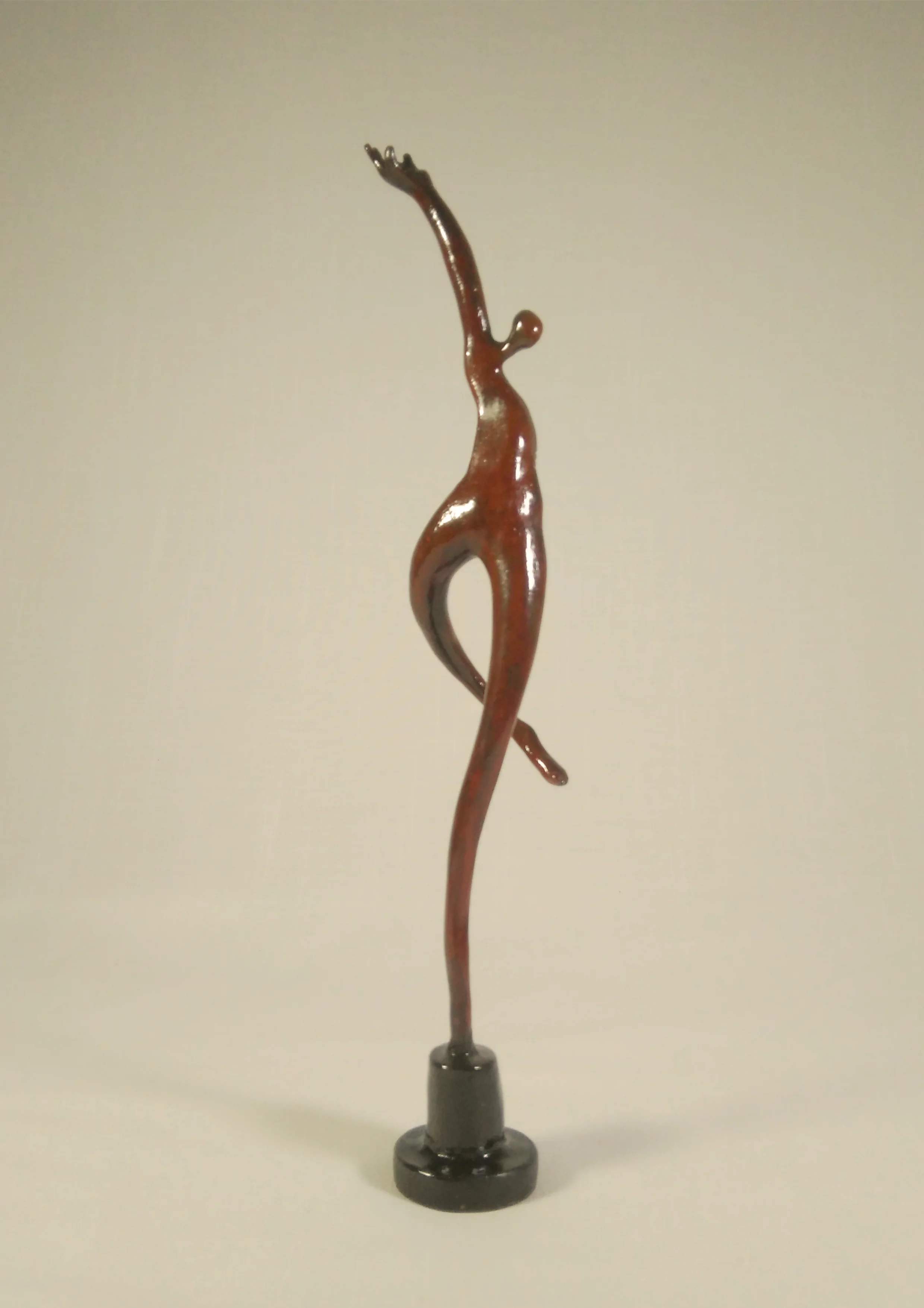 Figura con un apoyo en una base y brazo en alto.Tonos marrones. 37x9x8 centímetros, 222 gramos