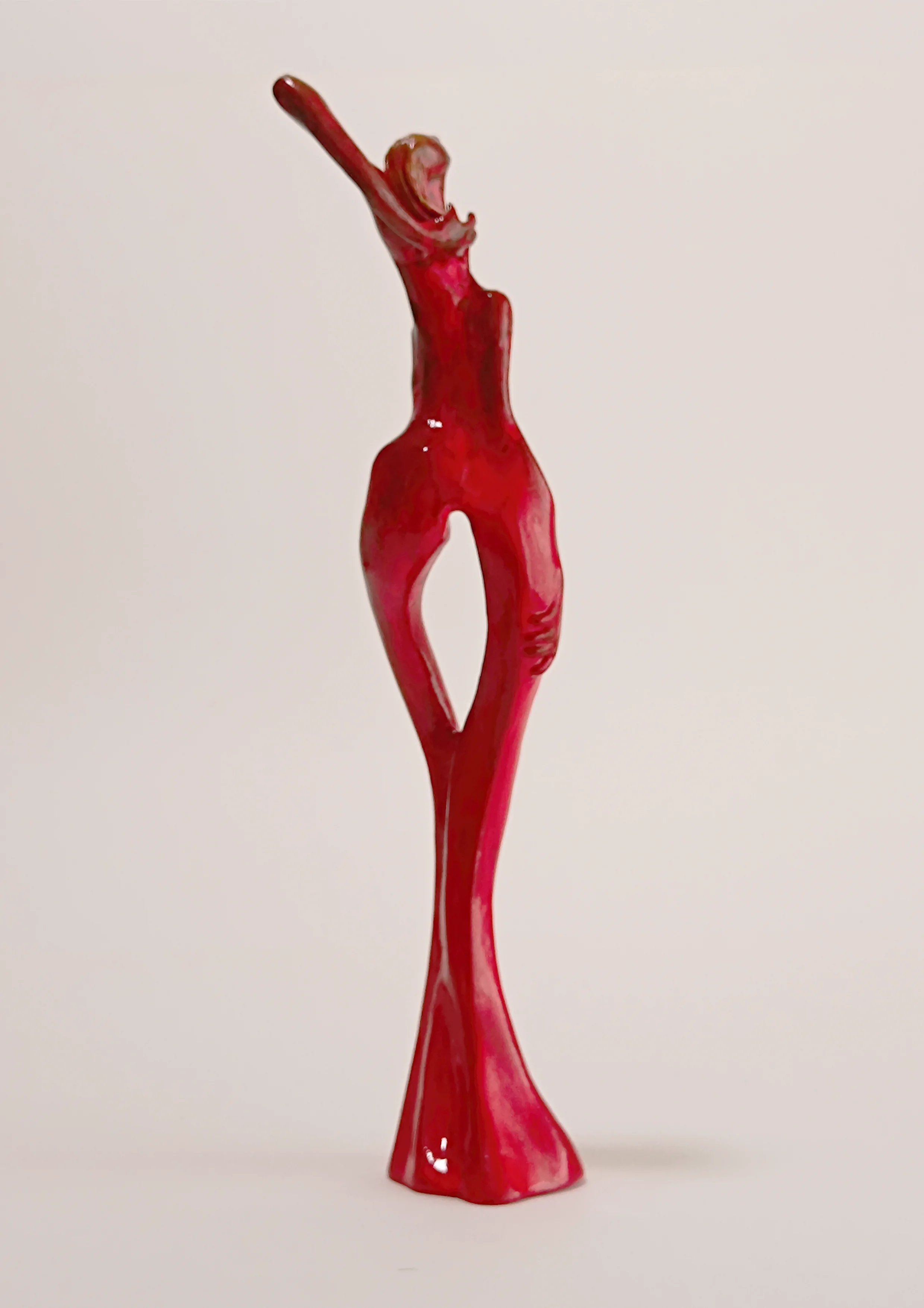 Figura en pie con un brazo levantadotocandose el pelo. 30x7x9 centímetros. Tonos rojos. 300 gramos